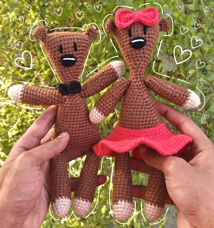 Two handmade crocheted teddy bears held by hands, perfect funny Valentine’s Day gifts to show true love and laughter.