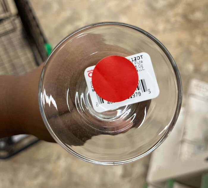 Hand holding a glass with a price tag inside showing selfish and stupid behavior in a teamwork context.