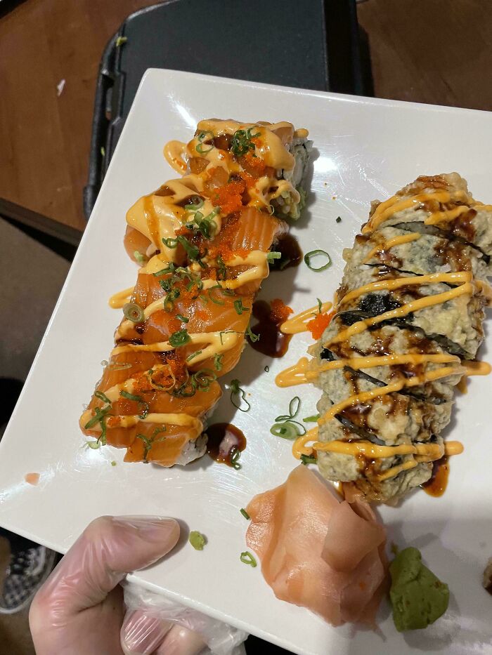 Two sushi rolls with sauce and garnishes on a white plate, illustrating selfish and stupid behavior in teamwork.