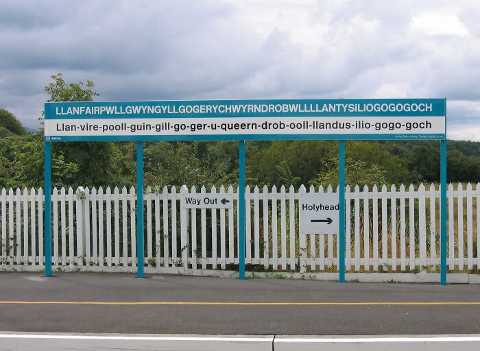 Train station sign displaying the unusually long place name Llanfairpwllgwyngyll, a unique location with a Wikipedia page.