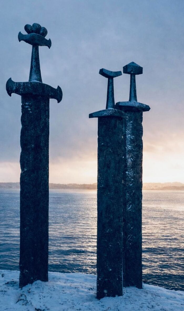 Three large ancient swords embedded in snowy ground by the water at dusk, illustrating rabbit holes exploration.