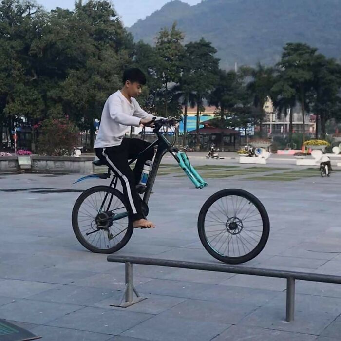 Person riding a bicycle with the front wheel missing, creating a surprising and unexpected photo moment.