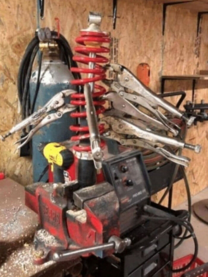 Improvised redneck engineering setup using clamps and spring in a workshop, showcasing creative but risky mechanical fixes.