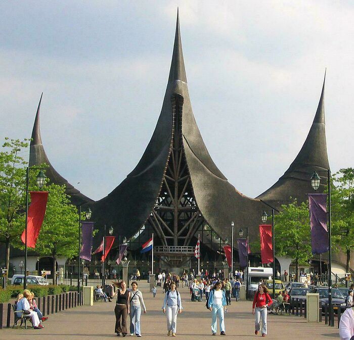 An imposing, spired building resembling a dark fantasy fortress, possibly built for an evil mastermind, with people entering.