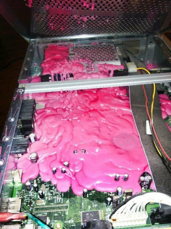Tech support mishap showing melted pink substance covering internal computer components and circuit board.