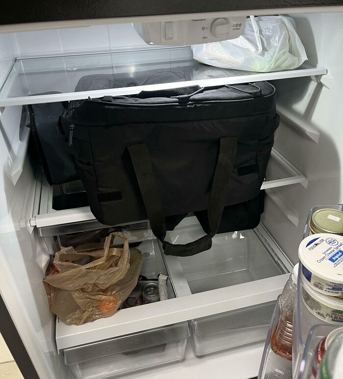 Black bag stored inside a refrigerator blocking shelves, illustrating selfish and stupid behavior in shared spaces.