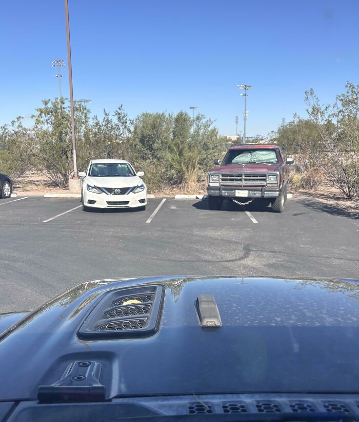Truck selfishly parked across two spaces in a nearly empty lot, showing lack of cooperation as a selfish and stupid act.