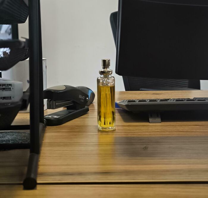 Bottle of yellow liquid placed on office desk with computer keyboard and stapler, illustrating selfish workplace behavior.