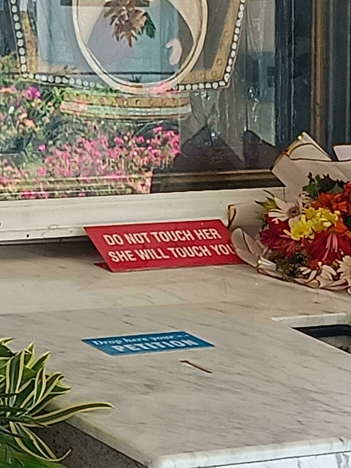 Red warning sign on marble surface reading do not touch her she will touch you, one of the scariest signs ever spotted in the wild.