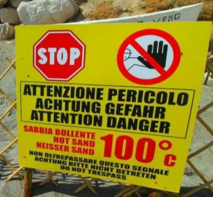 Warning sign showing hot sand temperature of 100 degrees Celsius, highlighting danger and no trespassing notices.