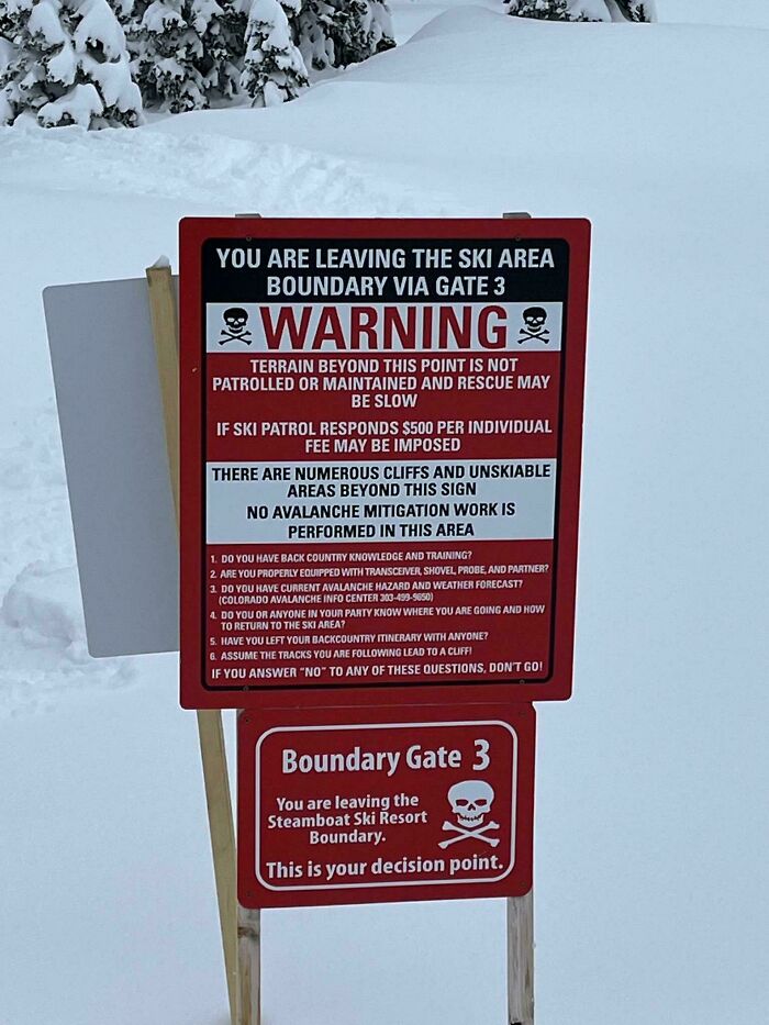 Warning sign at ski area boundary with skulls, cautioning about unpatrolled terrain and potential rescue delays, a scary sign spotted.