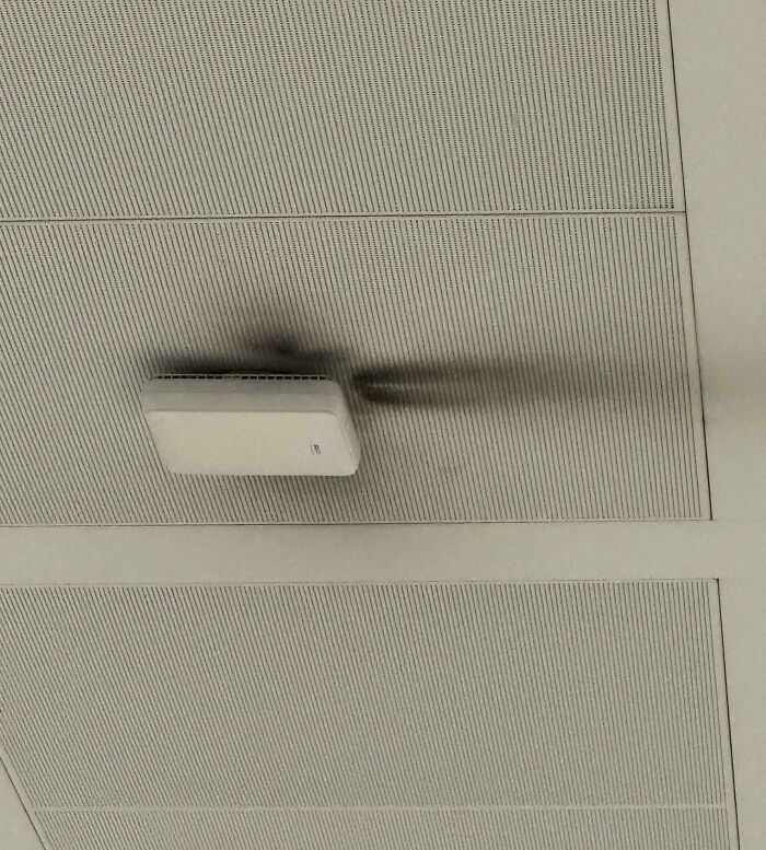 Ceiling tech device with black burn marks casting a shadow, illustrating tech support workers’ regrets in the profession.