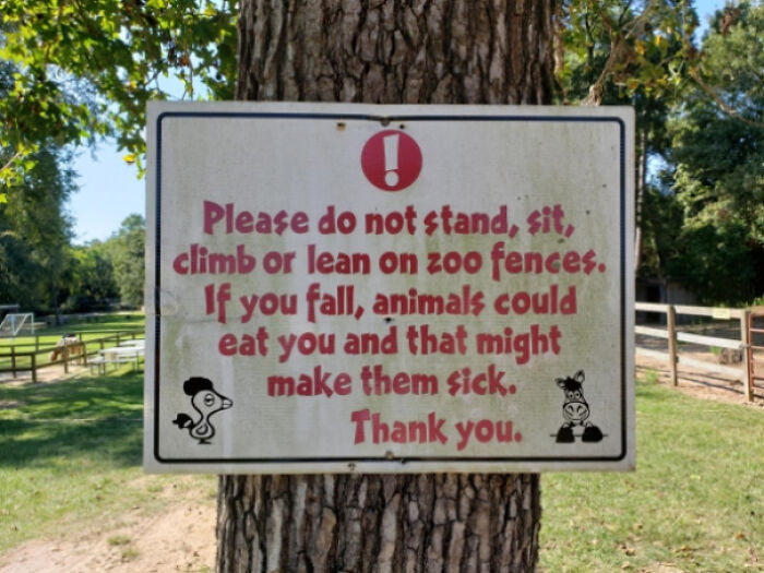 Warning sign on a tree at a zoo advising not to climb fences to prevent animals from getting sick.
