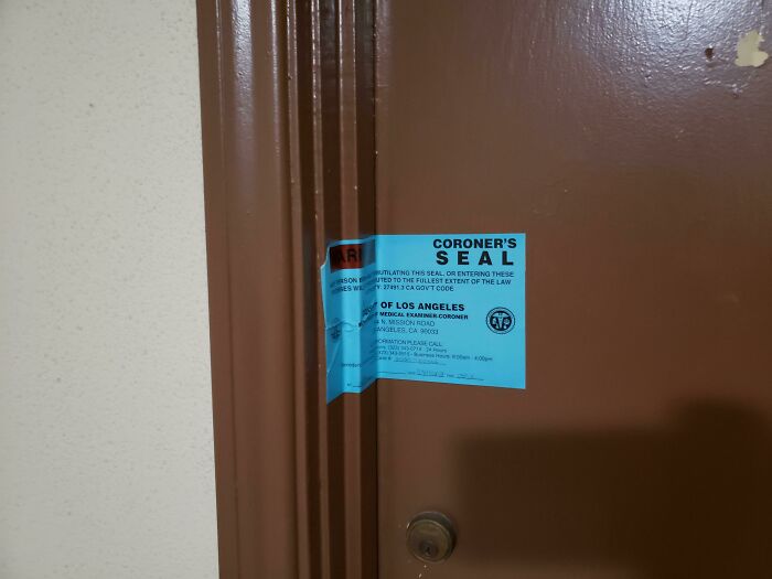 Blue coroner's seal taped across a brown door warning of possible inmates escaping, one of the scariest signs spotted in the wild.
