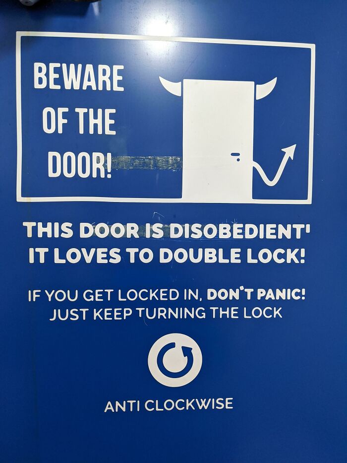 Warning sign on blue door with devil horns and tail illustration, humorously cautioning about escape and locking mechanisms.