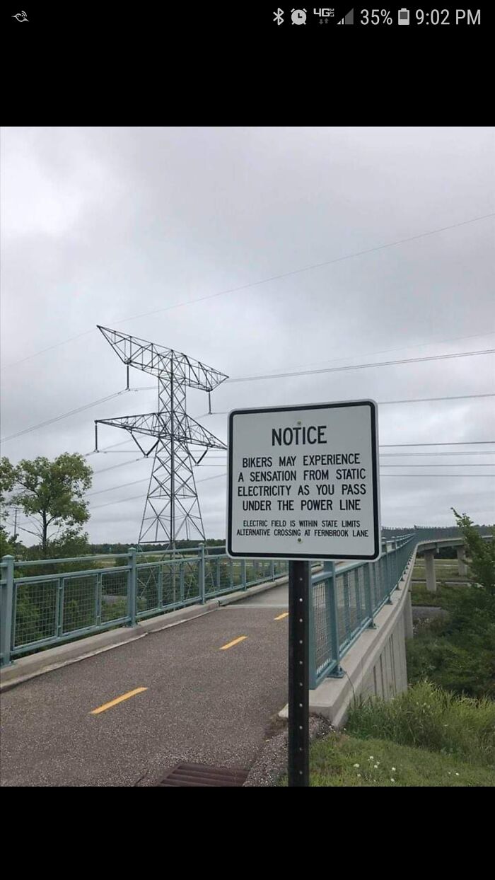 Warning sign on a bridge alerting bikers about static electricity sensation near power lines, one of the scariest signs spotted.