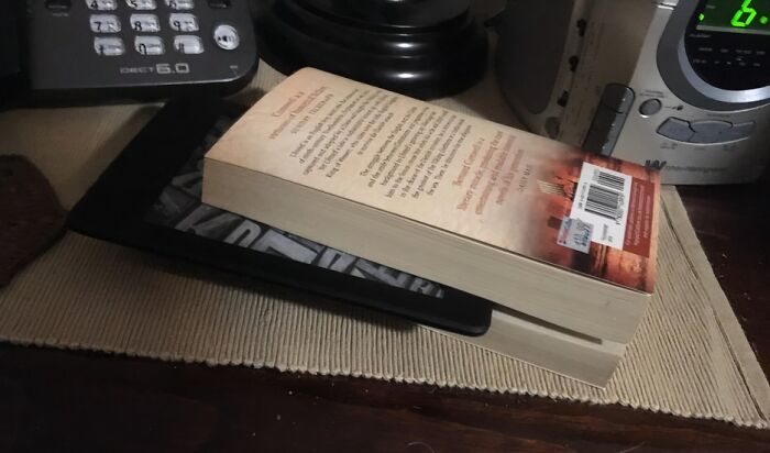 A book placed on top of a tablet, illustrating boomer technology use and failed attempts with modern devices.