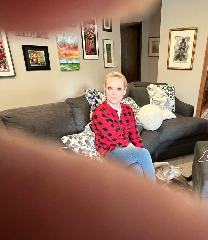 Woman sitting on a couch with a dog, photo partially obscured by a finger, illustrating boomers struggling with technology.