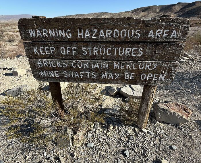 Warning hazardous area sign in desert warns of mercury bricks and open mine shafts, one of the scariest signs ever spotted in the wild.