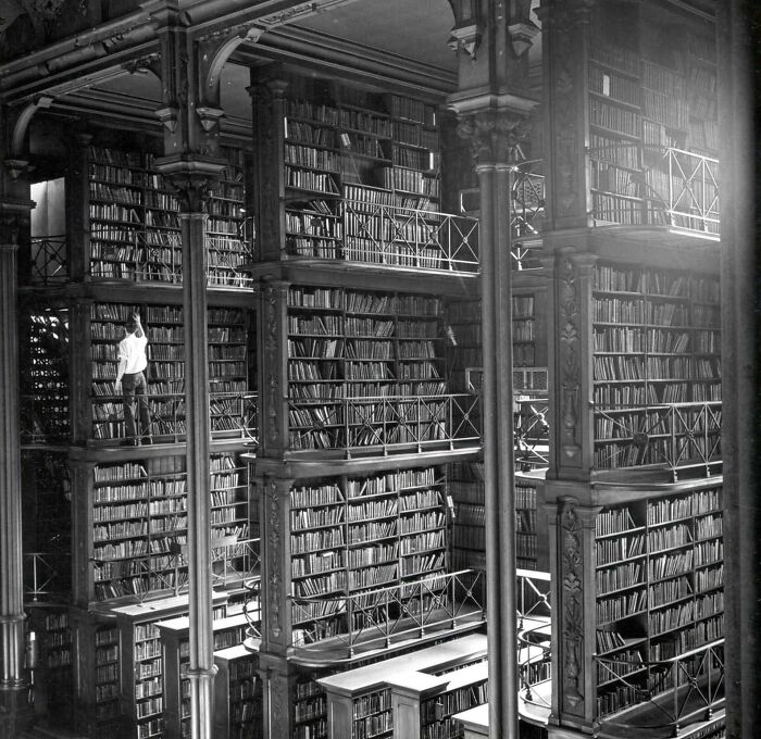 Historic multi-level library interior with ornate pillars and thousands of books in an interesting building lost over time.