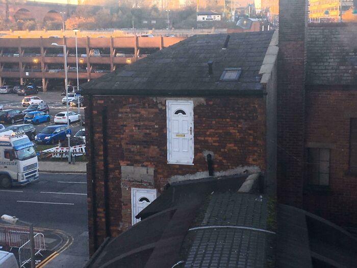 Two white doors installed on the exterior brick wall with no access, an example of architects failing at design.