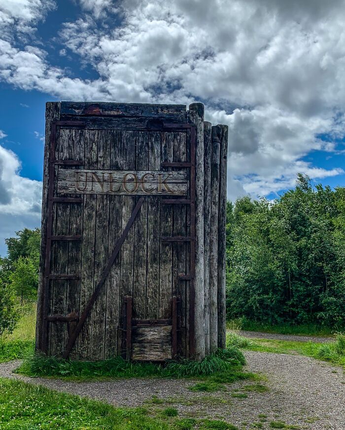 Old wooden door standing alone in nature, an example of architects failing with doors that lead absolutely nowhere.