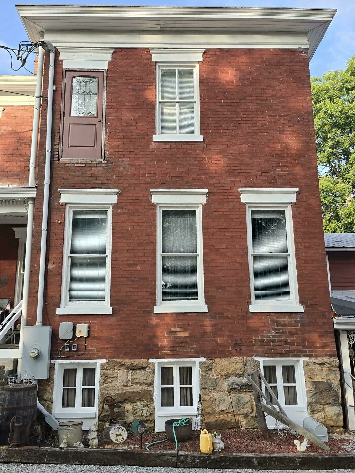 Brick building with a door on the second floor leading nowhere, showcasing architecture design failures and pointless doors.