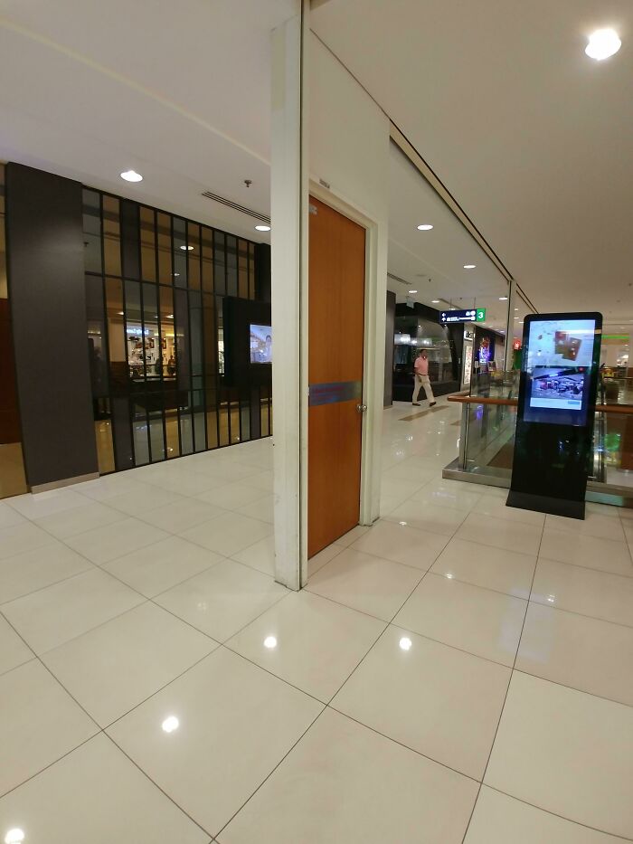 Door leading absolutely nowhere inside a modern building, showcasing an architectural design fail in a public space.