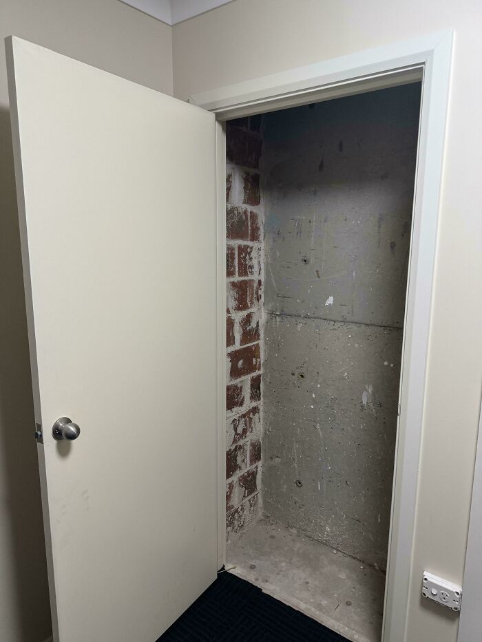 Door leading to a dead-end concrete and brick wall, showing a clear example of architects failing at their jobs.