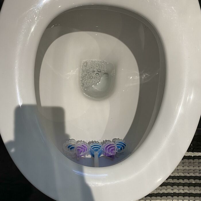 Toilet bowl with multiple cleaning tabs placed inside the rim, showing a partner’s frustrating and excessive habit.