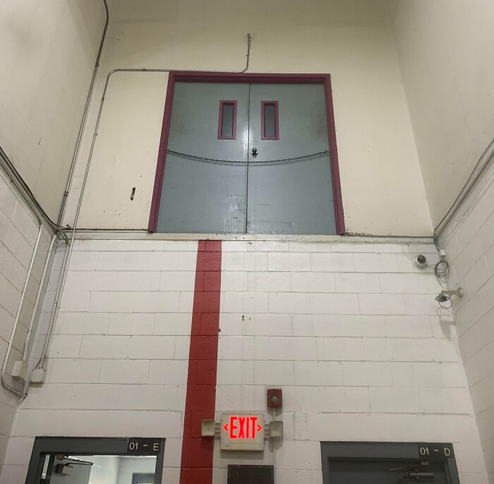 Double doors chained shut high above ground with no stairs or platform, an architect fail showing doors that lead nowhere.