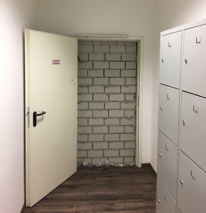 Door leading to a solid brick wall inside a hallway, showcasing a clear architectural fail with a door that leads nowhere.