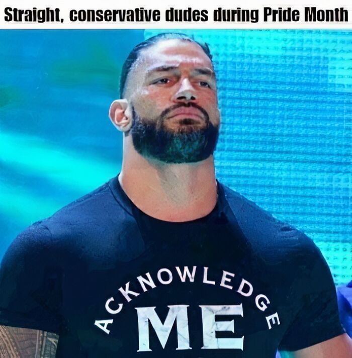 Man with beard and intense expression wearing a black shirt with the words acknowledge me in a hilarious meme style.