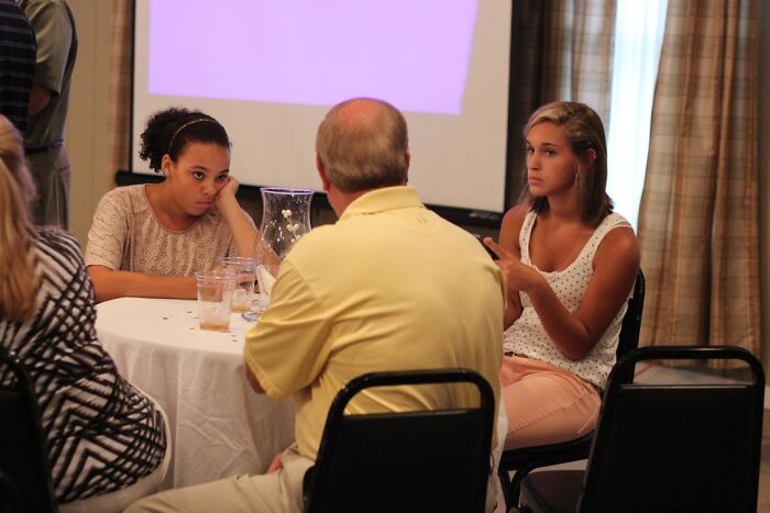 Three people seated at a table in a meeting room, one woman looking bored, fitting funny photos that say it all keyword.