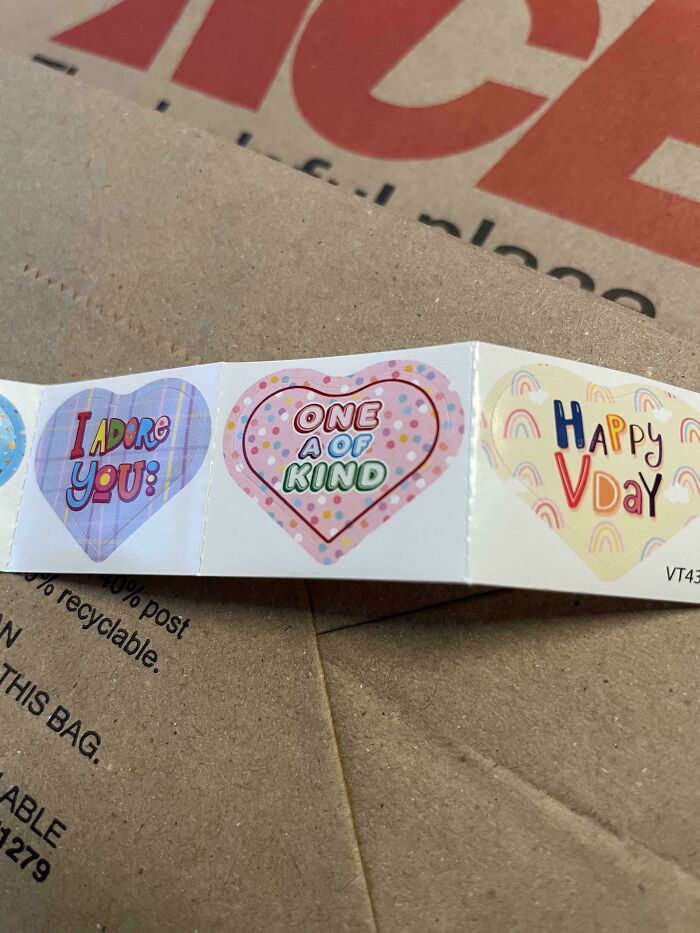 A close-up of a strip of heart-shaped stickers on a brown paper bag, with funny fails text visible.