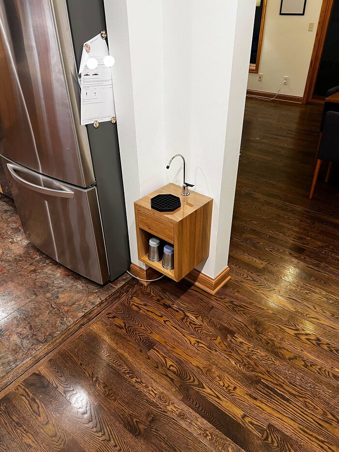 A wholesome photo showing what it means to be a great dad, with a small custom cabinet next to a refrigerator.