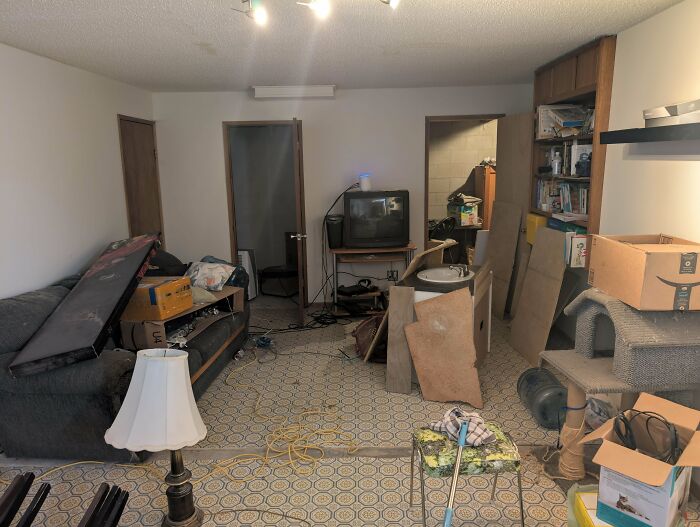 Cluttered living room showing frustrating habits like disorganized furniture, scattered cables, and unpacked boxes.