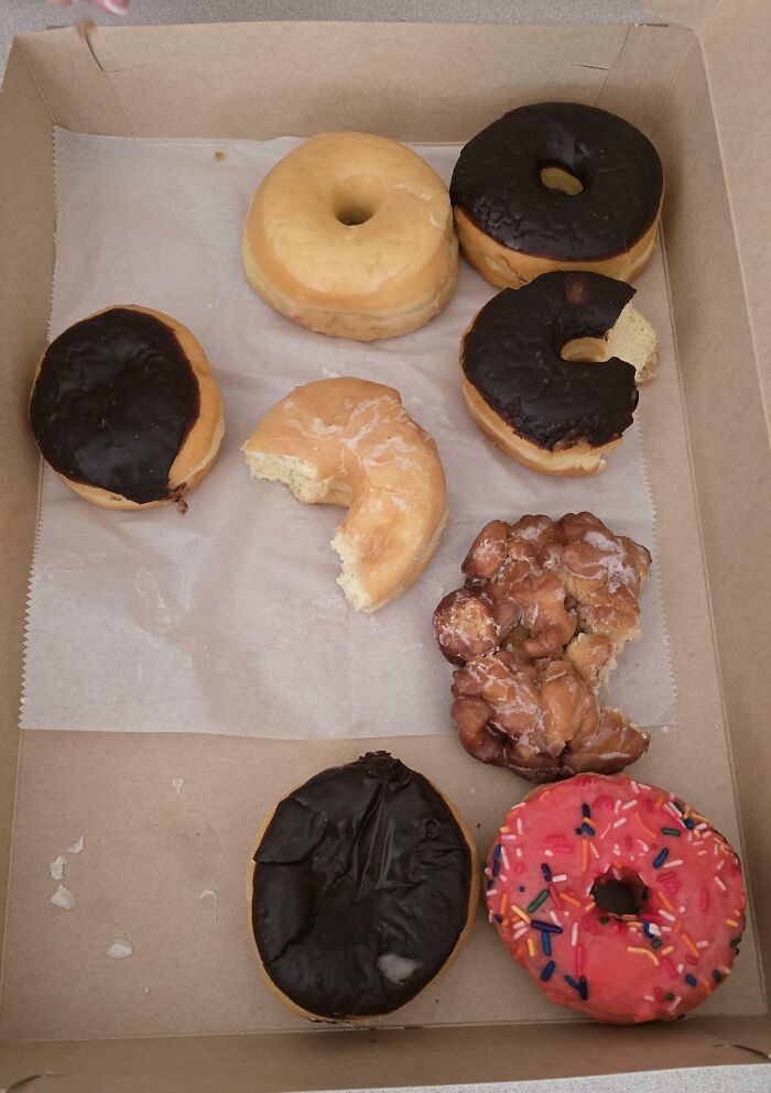Box of assorted donuts with some bitten missing pieces, illustrating partners’ most frustrating habits shared by 57 people.