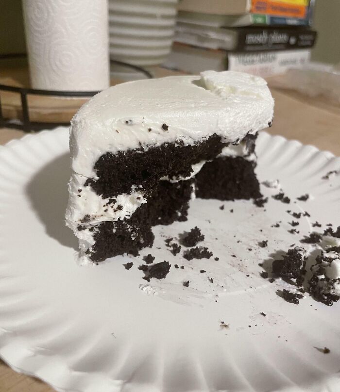 Partially eaten chocolate cake with white frosting on a paper plate showing a frustrating partner habit.