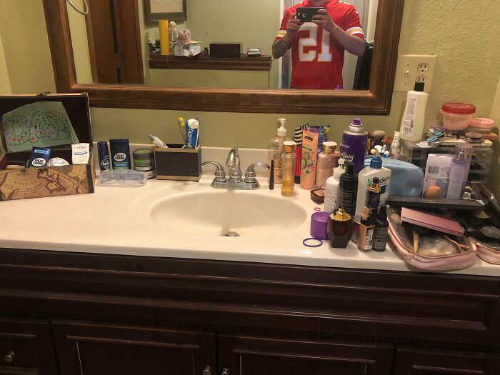 Bathroom sink cluttered with various toiletries and personal care items, illustrating frustrating partner habits shared by people.