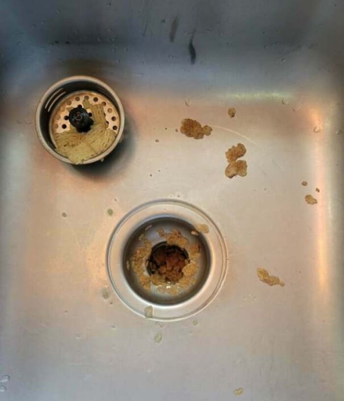Kitchen sink with food residue left in the drain and strainer, showing partners’ most frustrating habits in everyday chores.
