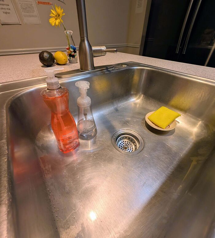 Kitchen sink filled with water and soap bottles showing a partner’s frustrating habit of not rinsing dishes properly.