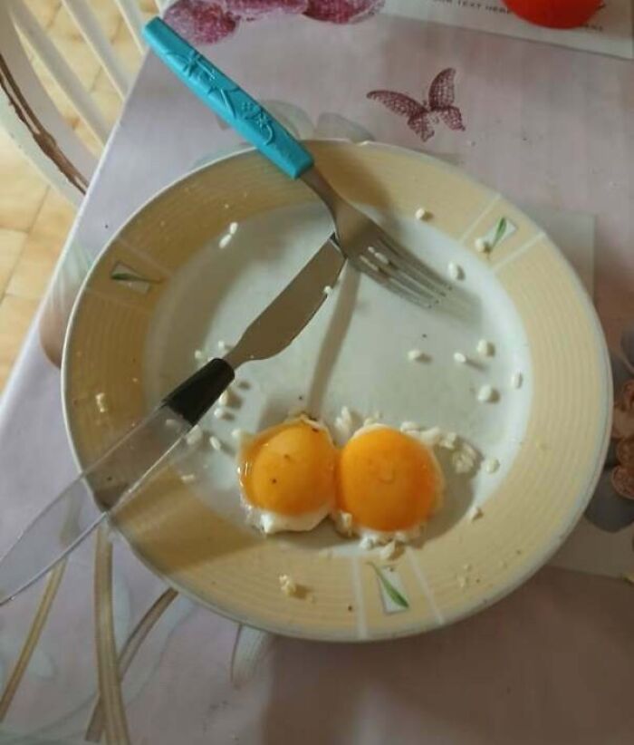 Plate with two fried eggs partially eaten, fork and knife placed oddly, showing a partner’s frustrating habits.