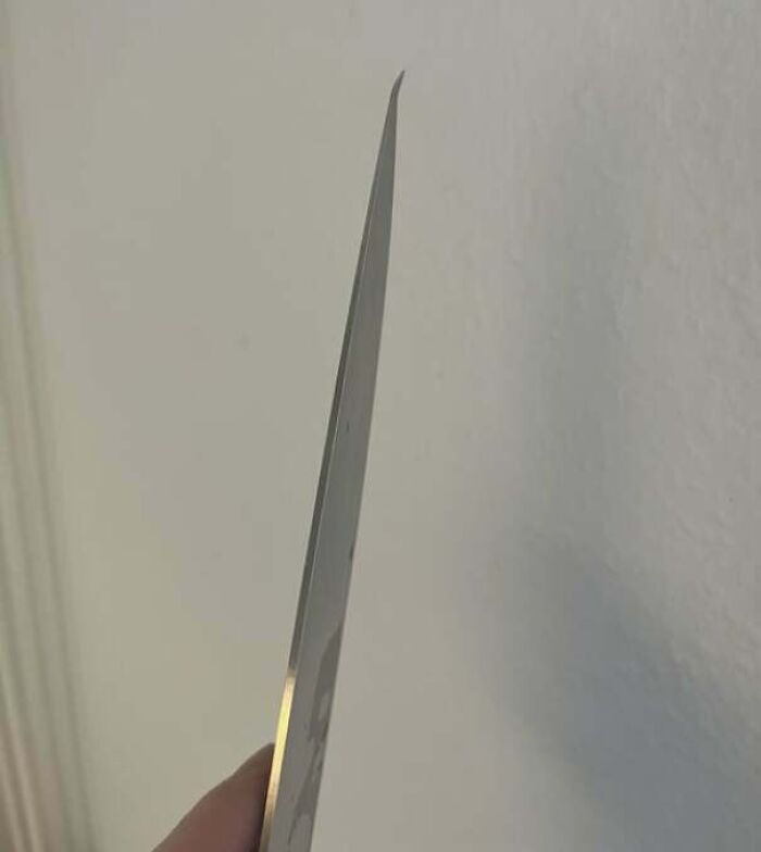 Close-up of someone holding a knife with a frustratingly dull blade, demonstrating a partner's annoying habit.
