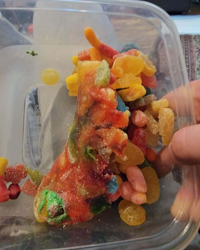 A gummy pizza slice mixed with various gummy candies in a plastic container showing a partner’s frustrating habit.