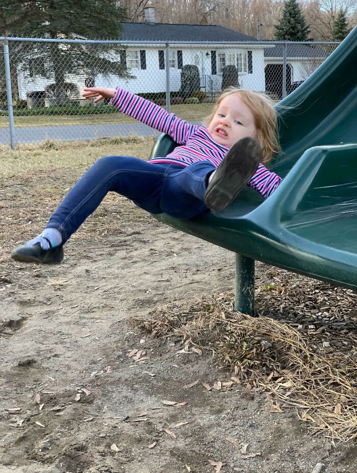 Young girl unexpectedly falling off a slide at a playground, capturing a way better pic than expected moment.