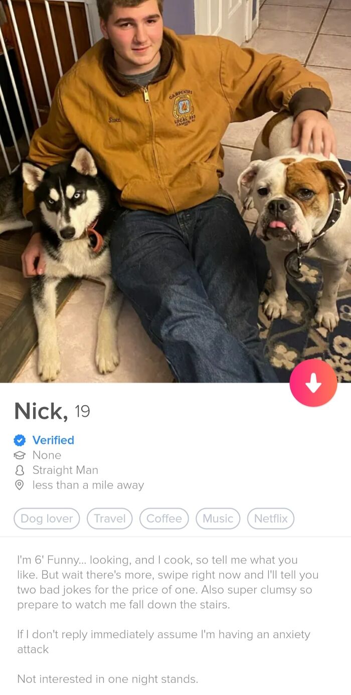 Young man in a brown jacket sitting with two dogs on a tiled floor in a quirky Tinder profile photo.