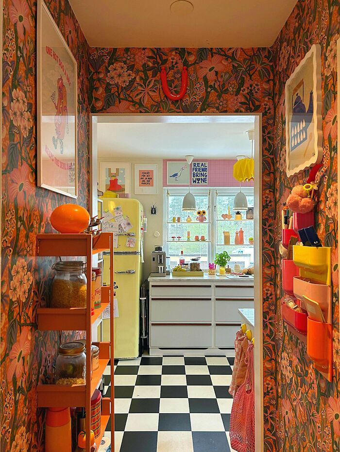 Colorful kitchen and hallway with bold floral wallpaper, checkerboard floor, and eclectic decor embracing more is more home style.