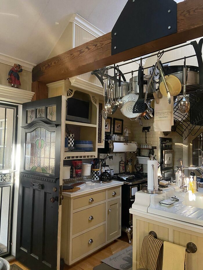 Cozy kitchen decked out with hanging pots, utensils, and vintage decor embracing a more is more home style design.