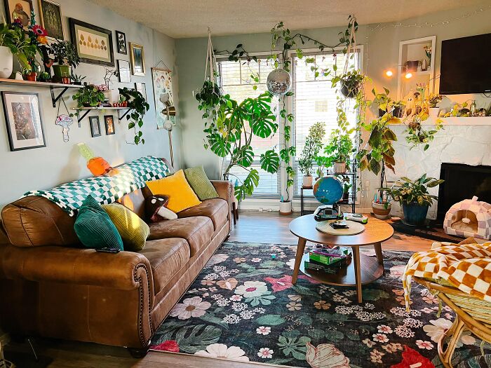 Cozy living room embracing more is more style with abundant plants, colorful pillows, wall art, and eclectic decor elements.